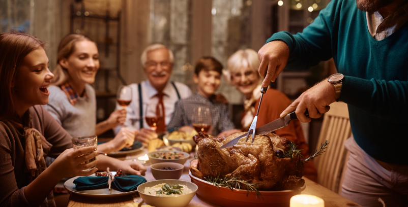 A family having dinner together. A man cutting a turky.